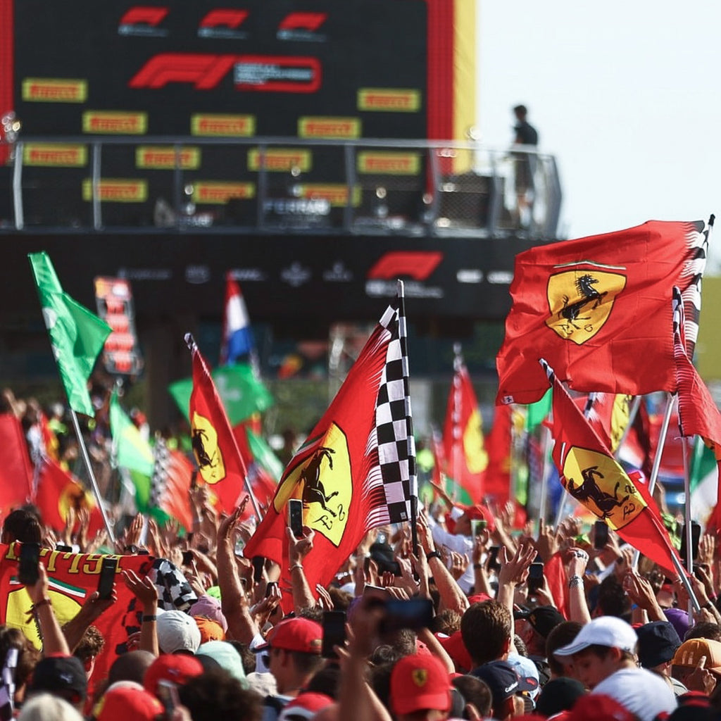 Group of Ferrari and Formula 1 fans with Ferrari flags under the F1 podium in Monza